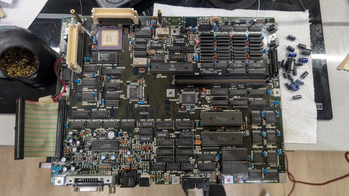 Sharp X68000 main board after recap with cleaned IC chips, RAM modules, new oscillator installed, and CR2032 battery mod visible among component work.