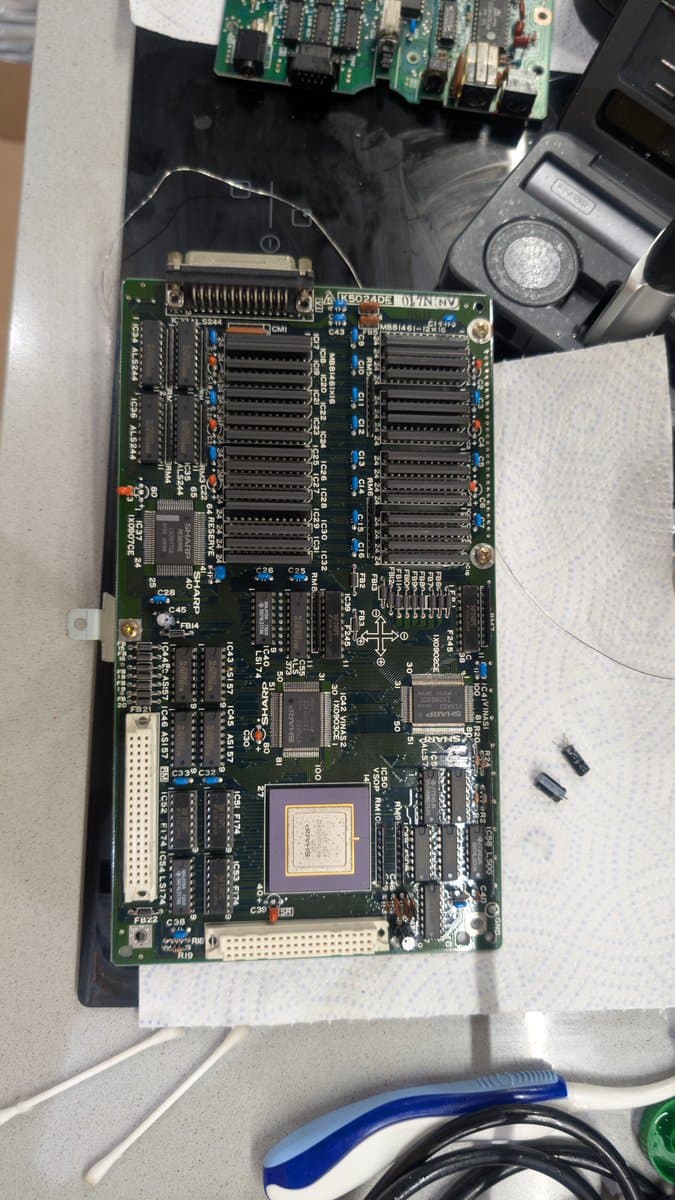 Sharp X68000 main board after cleaning and recapping, showing CPU, RAM chips, and freshly installed oscillator with CR2032 battery mod.