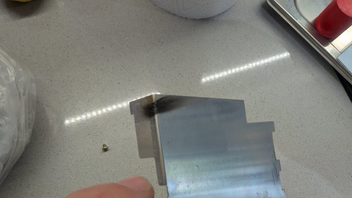 Burnt metal shield with charred component damage next to loose capacitor on workbench during X68000 restoration.