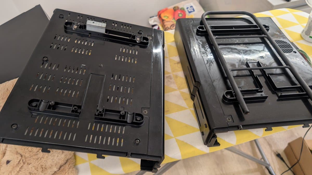Sharp X68000 case bottom panels showing floppy drive mechanisms and ventilation holes during restoration cleaning and lubrication work.