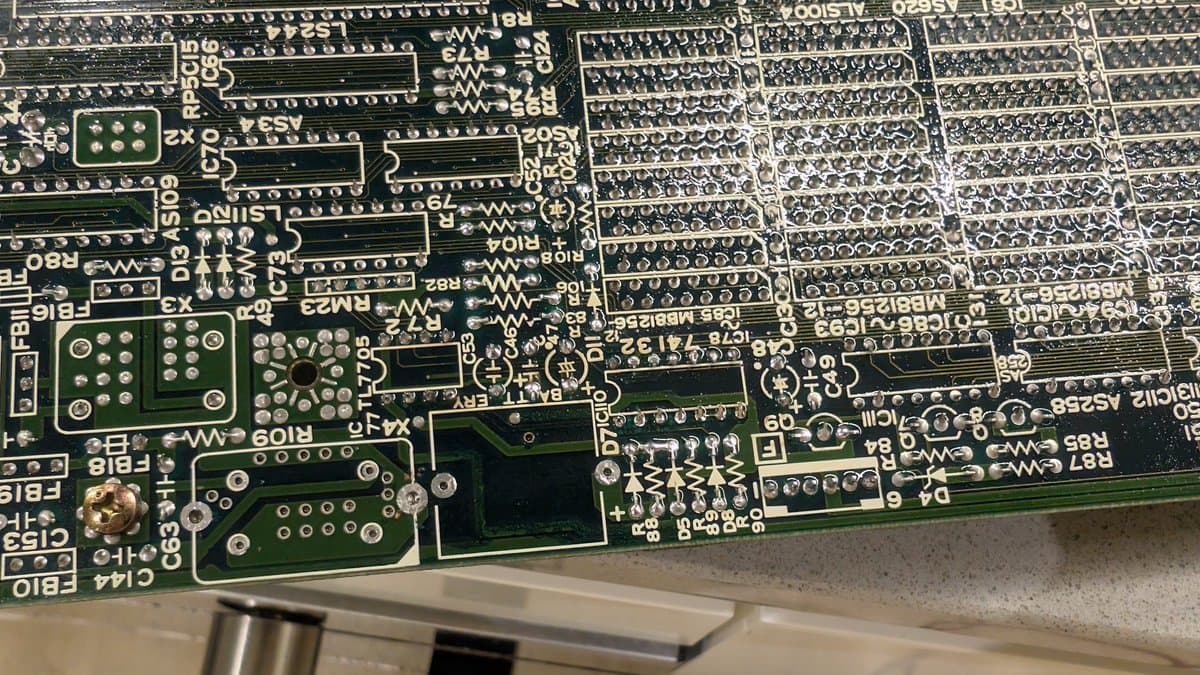 Close-up of X68000 motherboard showing resoldered components near battery leak area and new oscillator installation; green PCB with resistors and capacitors visible.