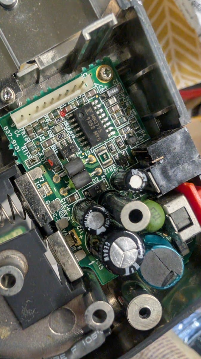 Corroded Game Gear power supply board with leaking capacitors, poor solder joints, and dangerous PSU bodge creating fire hazard.