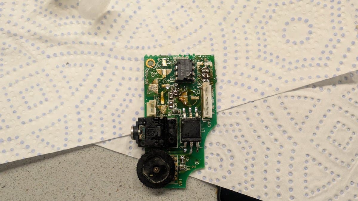 Game Gear audio board on dotted mat with tweezers, showing cleaned PCB, black connectors, and various components after ultrasonic cleaning.