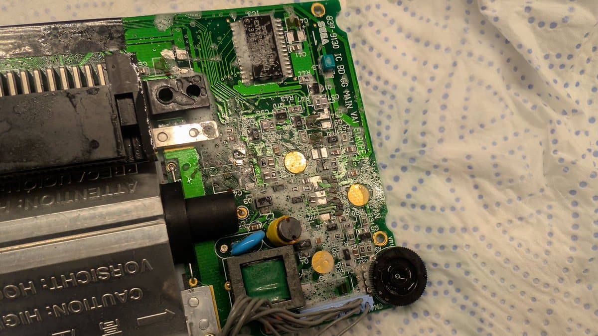 Game Gear main board cleaned, showing deteriorated button pad contacts from capacitor leakage and yellow electrolytic capacitors ready for replacement.