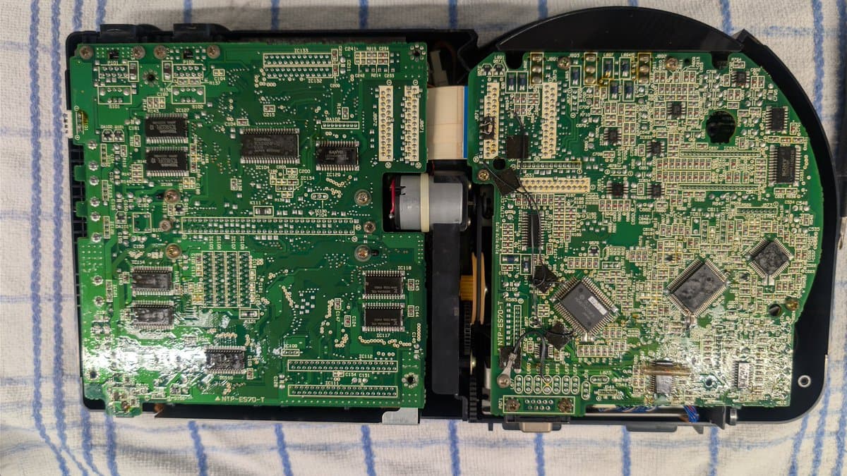 Wondermega HWM-5010 opened showing two interconnected PCBs with visible ICs, connectors, and transformer; console mid-disassembly.