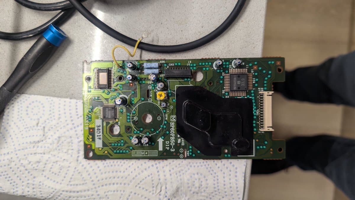 FM Towns Marty CD-ROM drive PCB after recapping, showing capacitors, ICs, and connectors on green circuit board with cables attached.
