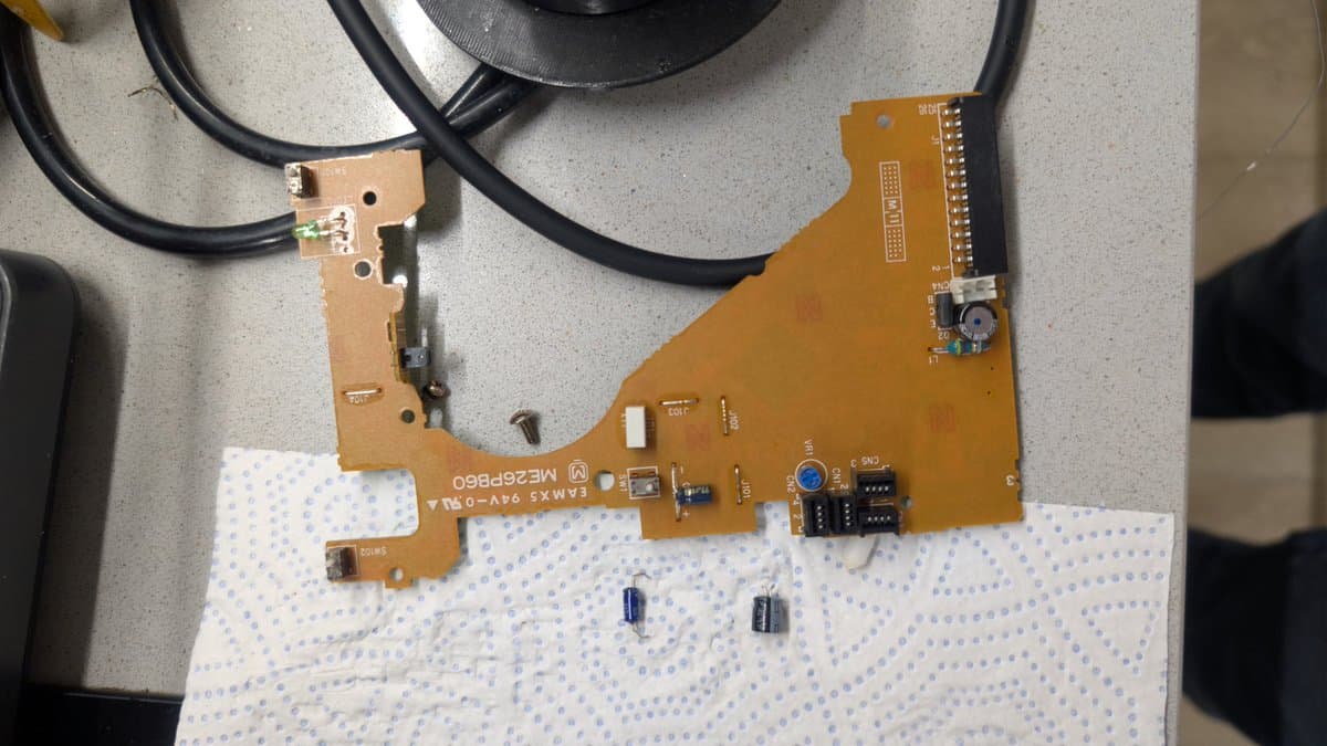 Fujitsu FM Towns Marty floppy drive PCB mid-recap; tantalum capacitors removed, cleaned board with flux residue visible on white mat.