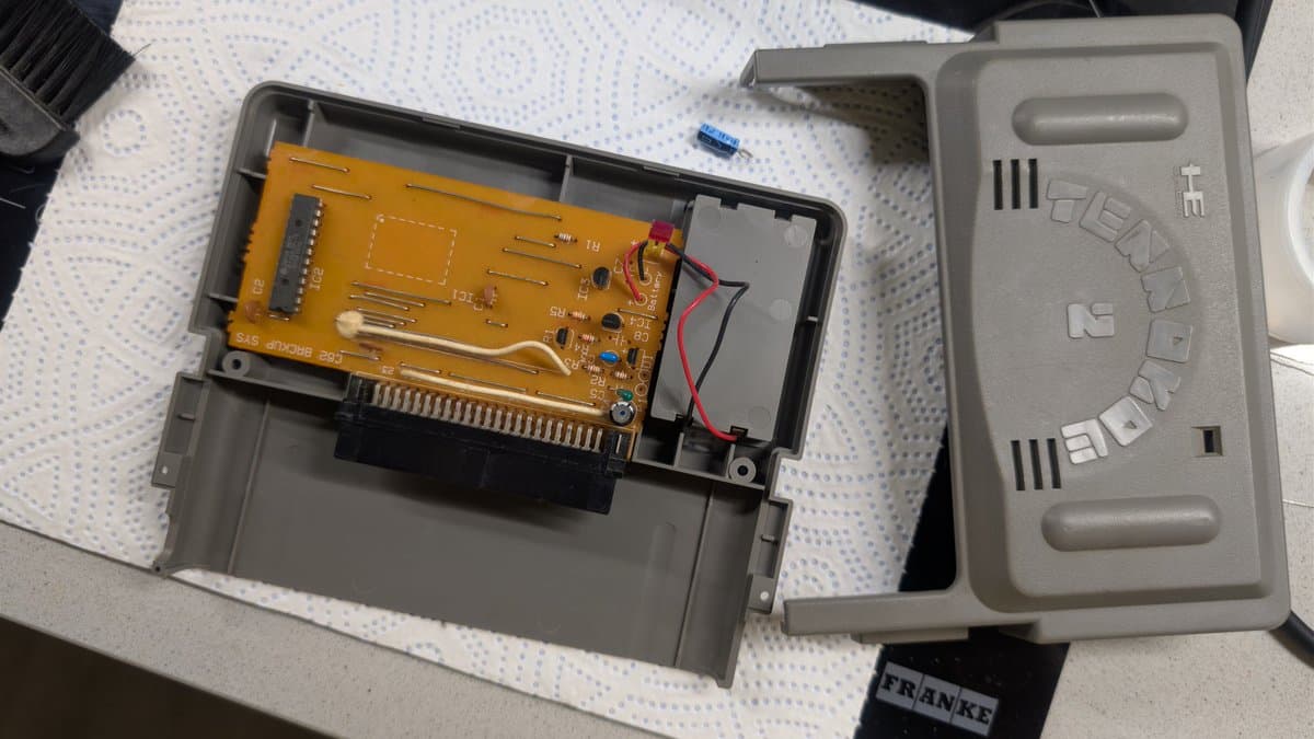 Ten No Koe 2 circuit board with original Hudson Soft batteries removed, showing yellow PCB and black connector in gray plastic housing.