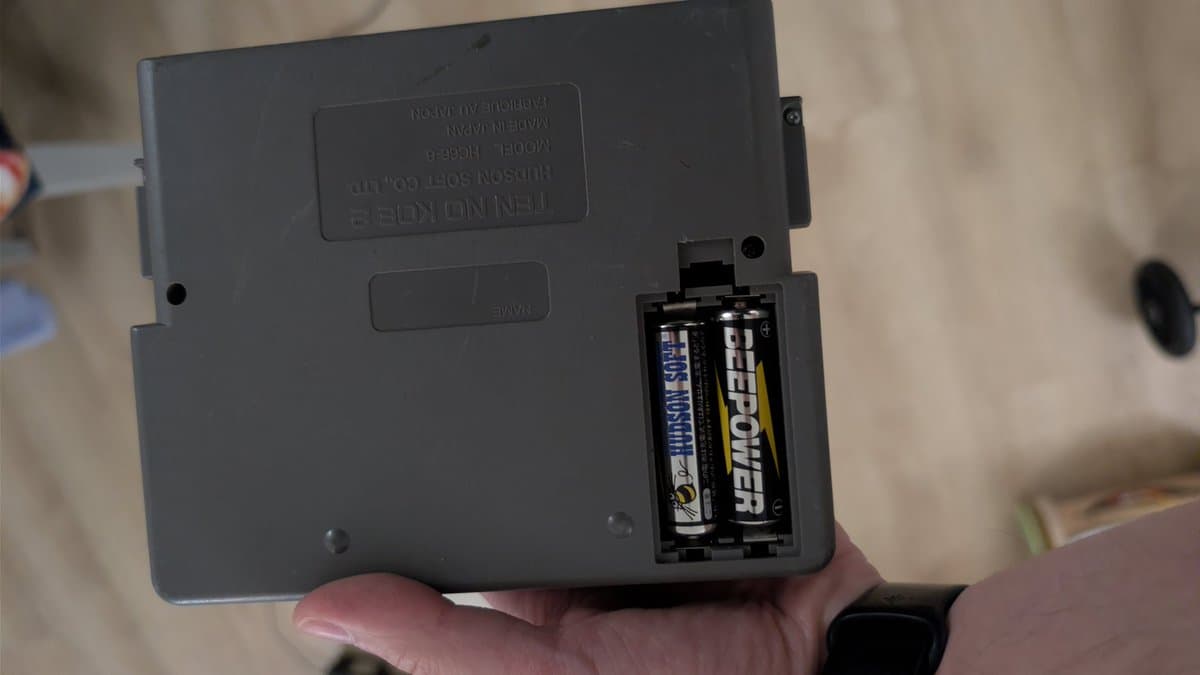 NEC Ten No Koe 2 battery compartment showing original Hudson Soft branded batteries after removal during recap repair.
