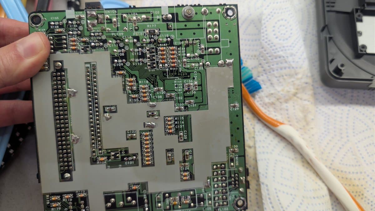 PC Engine CoreGrafx mainboard during recap with visible capacitors, resistors, and solder joints undergoing replacement maintenance work.