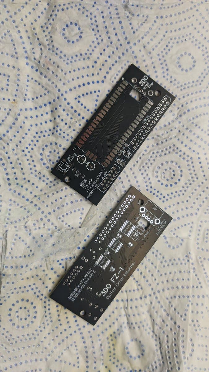 Two black PCBs for 3DO ODE (optical drive emulator) modules laid on patterned fabric, showing component layouts and connectors.