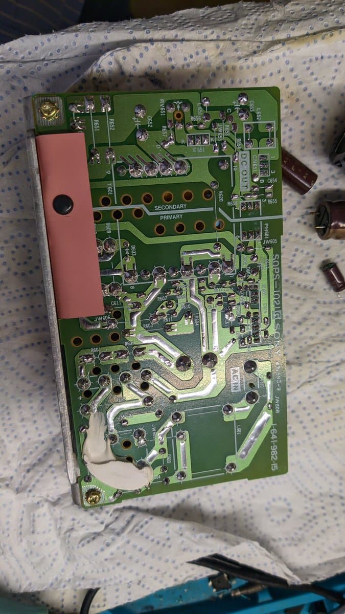 Sony PVM-9041Q PSU board with pink heatsink; recapped with fresh solder joints visible on primary/secondary coil areas.