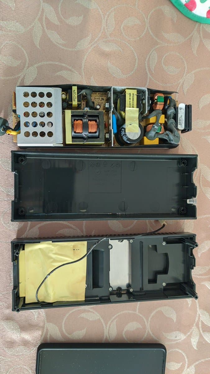 Disassembled Xbox 360 S power supply showing capacitors, transformers, and circuit boards during recap and reflow repair work.