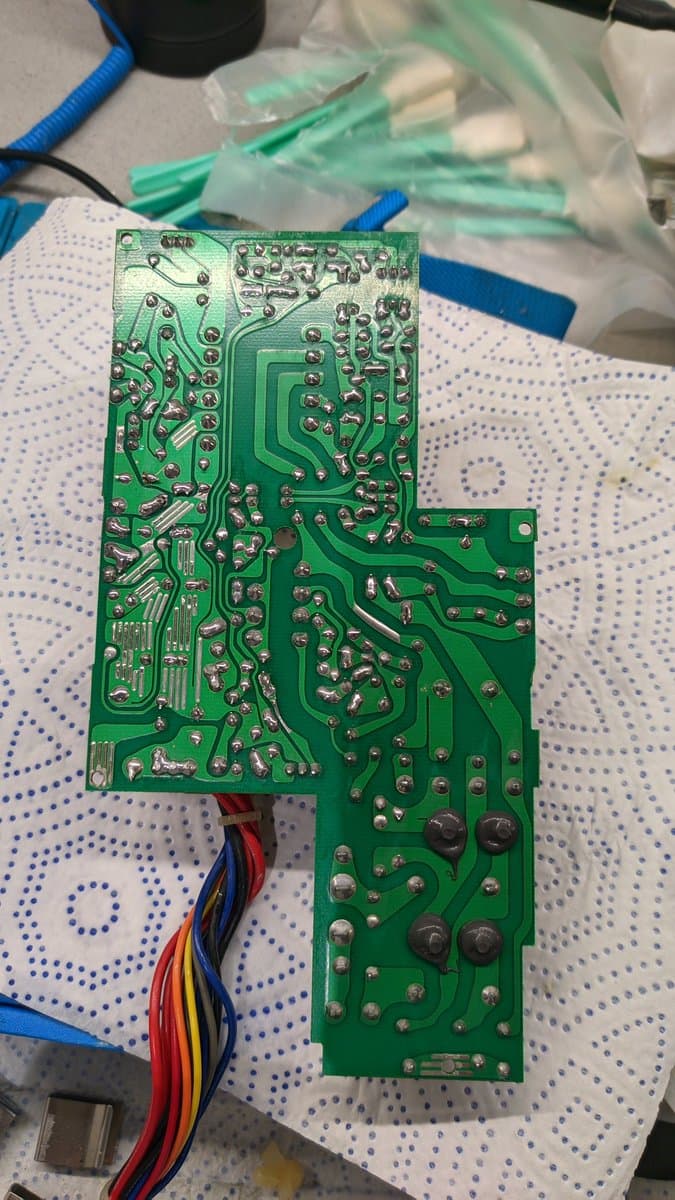 Sharp X68000 Pro II power supply PCB with soldered components, electrolytic capacitors, and color-coded wires; reverse-installed capacitor caused magic smoke damage.