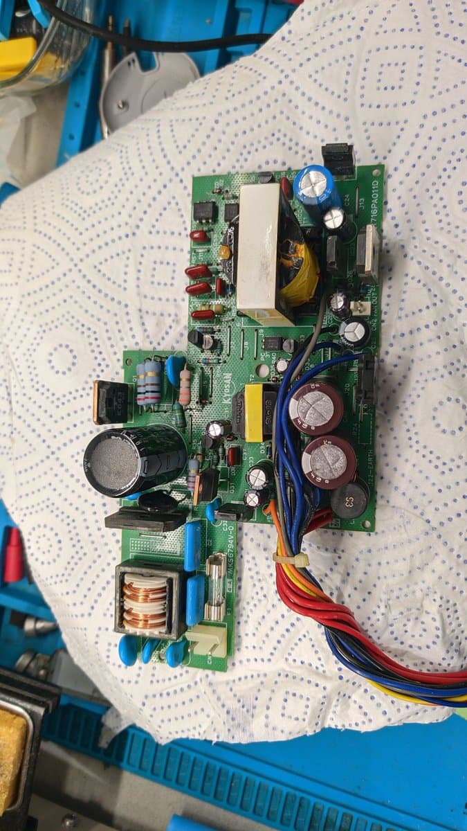 Sharp X68000 Pro II power supply board with reversed filter capacitor blown out, showing damaged components and replaced electrolytic capacitors during restoration.