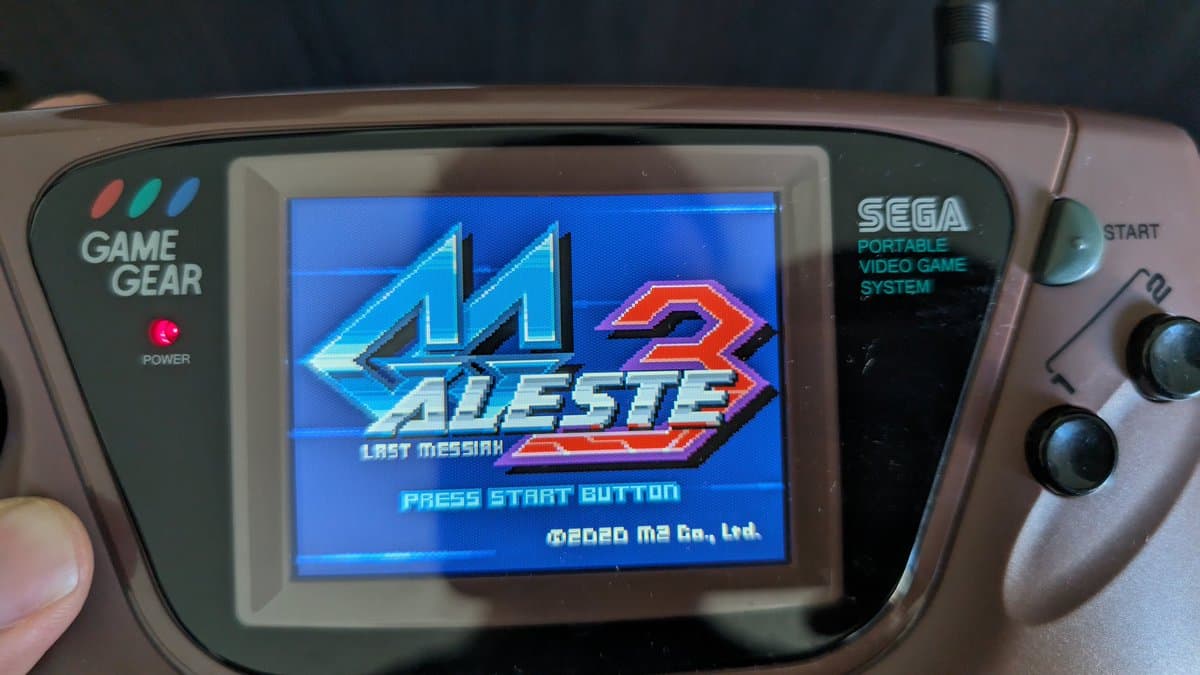 Sega Game Gear displaying Aleste 3 title screen after IPS mod repair, showing restored LCD, speaker, and clock line bodge wire fix.
