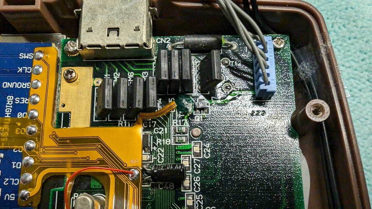 Clock line bodge wire soldered to TP10 pad with UV curing solder mask, flex cable damage repair on Game Gear mainboard.