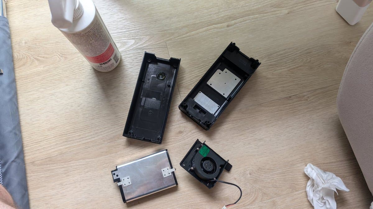 Xbox 360 E PSU and internal components disassembled on workbench with cleaning spray and tissues, showing replaced capacitors and fan.