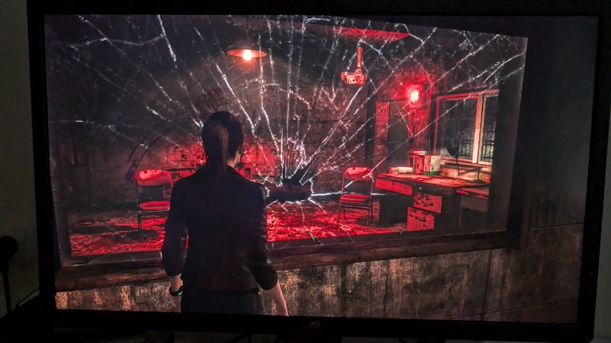 Xbox 360 E running game after PSU recap and board reflow repair; character in red-lit courtyard scene displaying restored functionality.