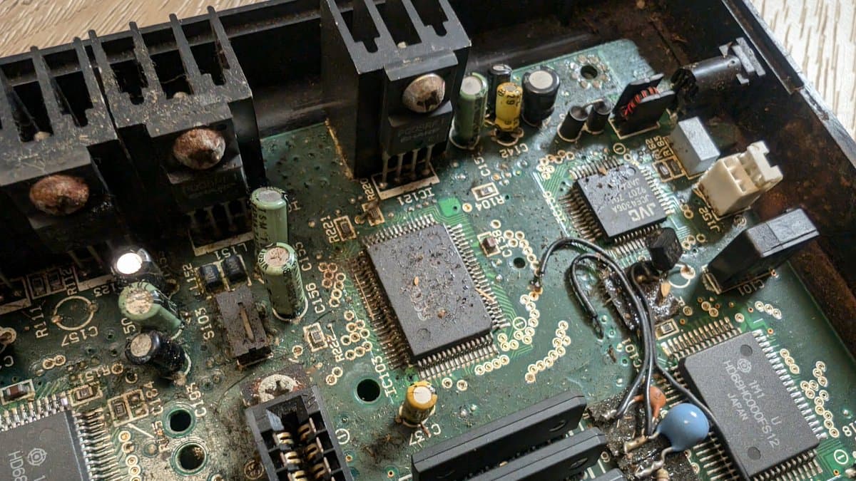 Corroded Wondermega mainboard showing oxidation on capacitors, damaged traces, and component deterioration requiring restoration work.