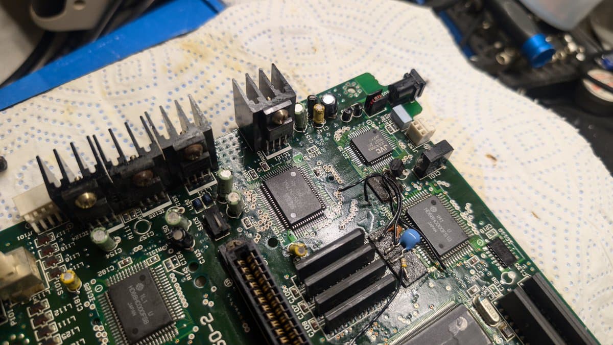 Cleaned Sega Wondermega mainboard showing two heatsink-mounted ICs, RAM chips, and various components on breadboard after isopropyl restoration.