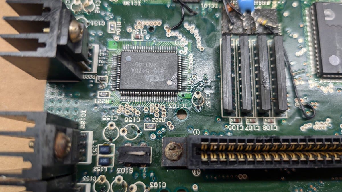 Main board capacitor removal in progress; desoldered regulators visible, corroded components, multi-pin IC chip exposed on green PCB.