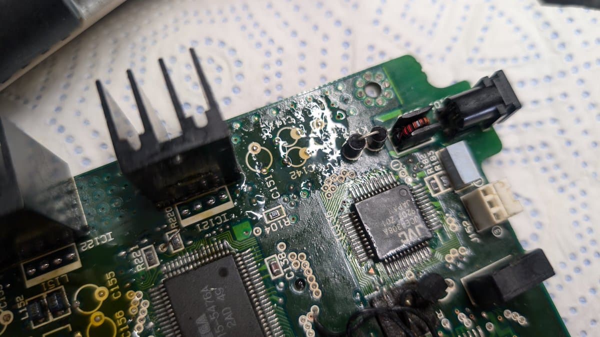 Circuit board flooded with solder and tacky flux to remove corrosion and electrolyte damage from water-damaged Wondermega motherboard.