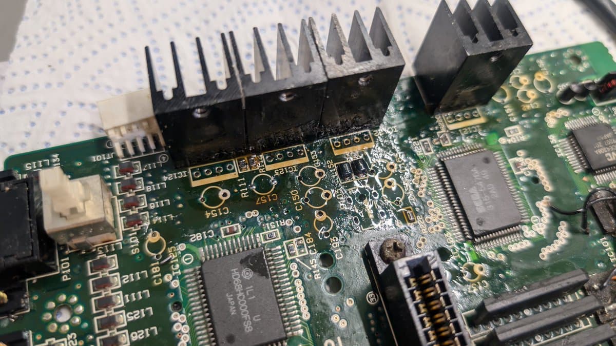 Close-up of Wondermega motherboard showing repaired section with new heatsinks installed on power regulation components and cleaned PCB traces.
