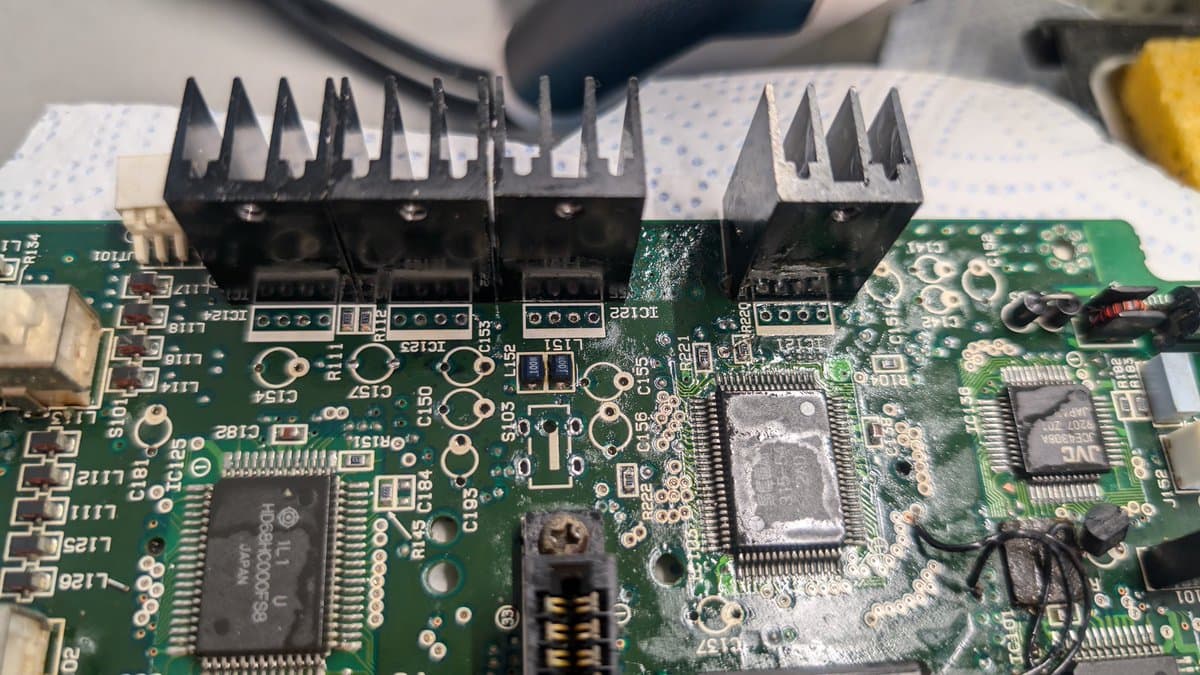 Sega Wondermega PCB with four black heatsink modules mounted across top, showing corrosion cleanup and component restoration work.