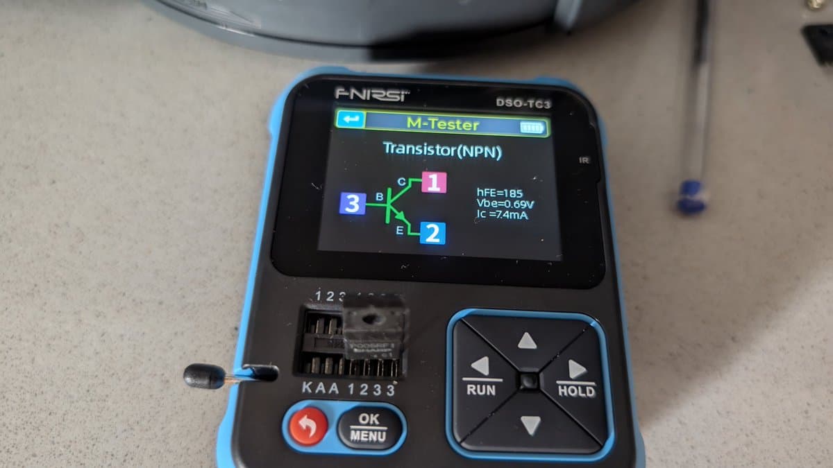 FNirsi DSO-TC3 multimeter displaying NPN transistor test results: hFE=105, Vbe=0.69V, IC=7.4mA during Wondermega regulator testing.
