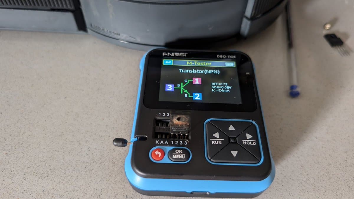 ANSI multimeter displaying NPN transistor test results (hFE=172, Vbe=0.0BV, Ic=74mA) during Wondermega regulator diagnostics.