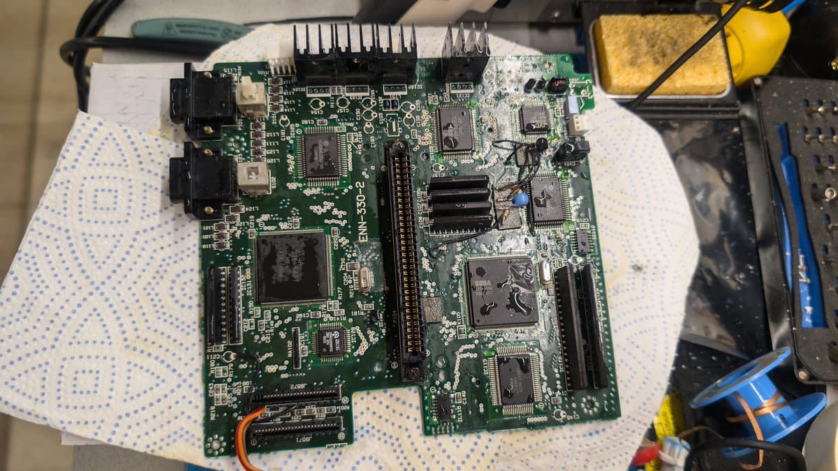 Wondermega main board after ultrasonic cleaning, showing cleaned PCB with visible ICs, RAM chips, connectors, and soldering tools nearby on work mat.