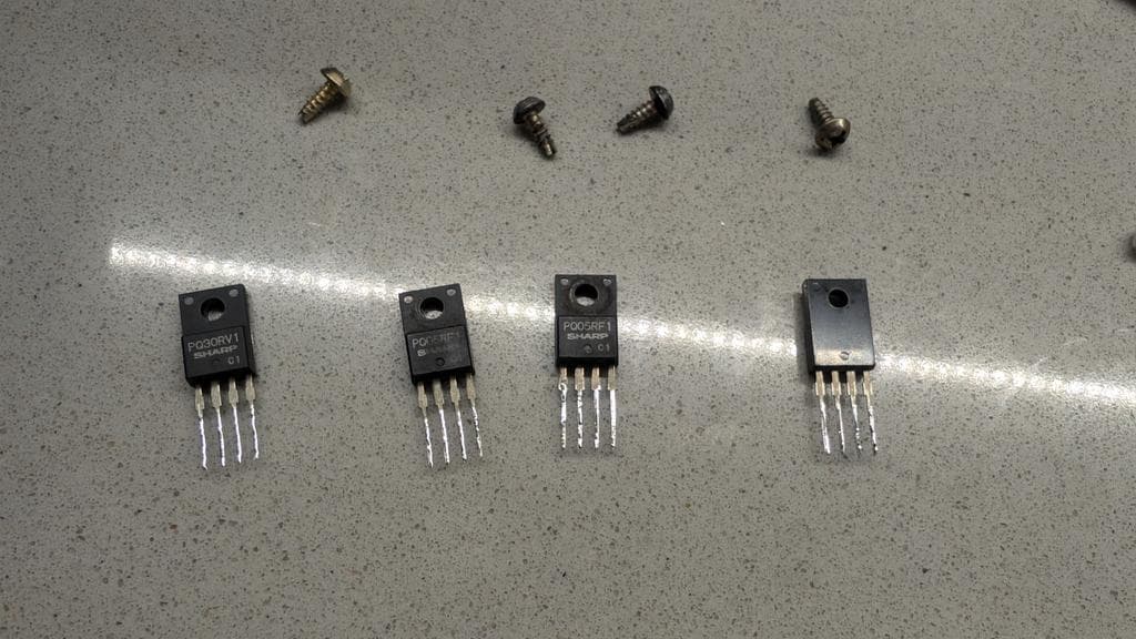 Four voltage regulators with tinned legs and small screws on workbench during Wondermega restoration.
