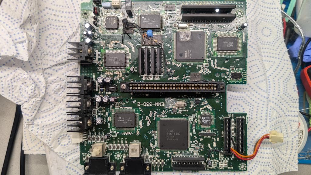 Sega Wondermega main board showing corroded components, missing parts, and broken traces requiring cartridge connector removal for full assessment.