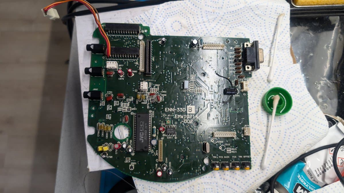 Wondermega motherboard ENN-330 with capacitor replacement work, visible corrosion damage and solder joints during CD freezing issue diagnosis.