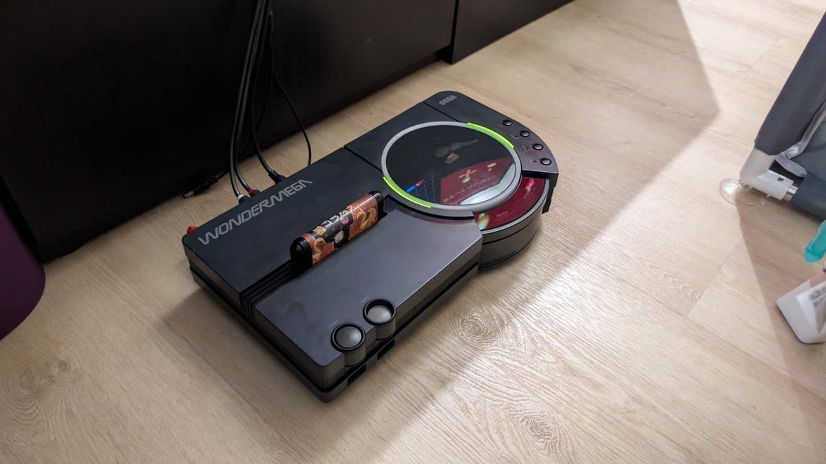 Sega Wondermega HWM-5010 restoration in progress on wooden desk, displaying functional Mega Drive side with lit display screen.