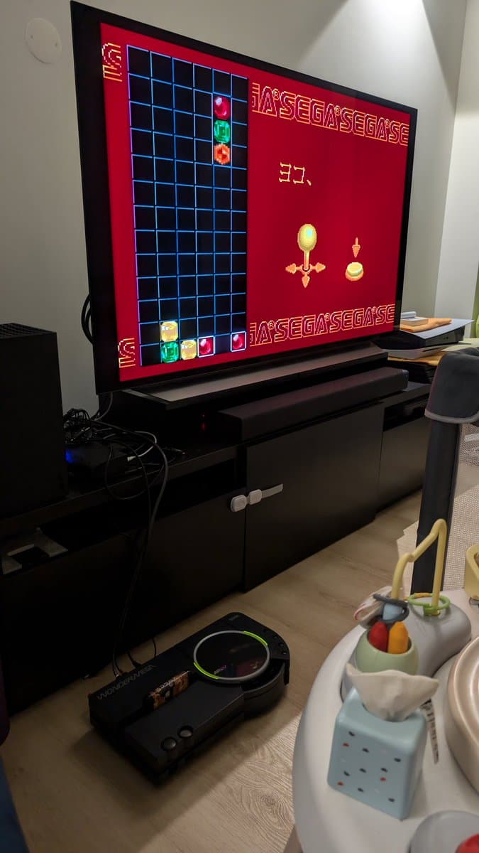 Sega Wondermega displaying Puyo Puyo via Mega Drive mode on TV; game controller visible below screen during restoration testing.