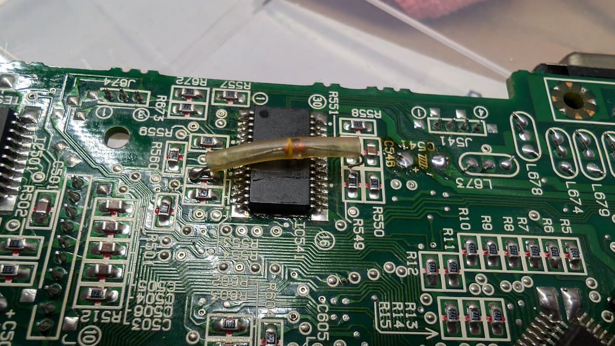Soldering iron replacing BTL driver IC on corroded Sega Wondermega circuit board with visible component damage and corrosion.