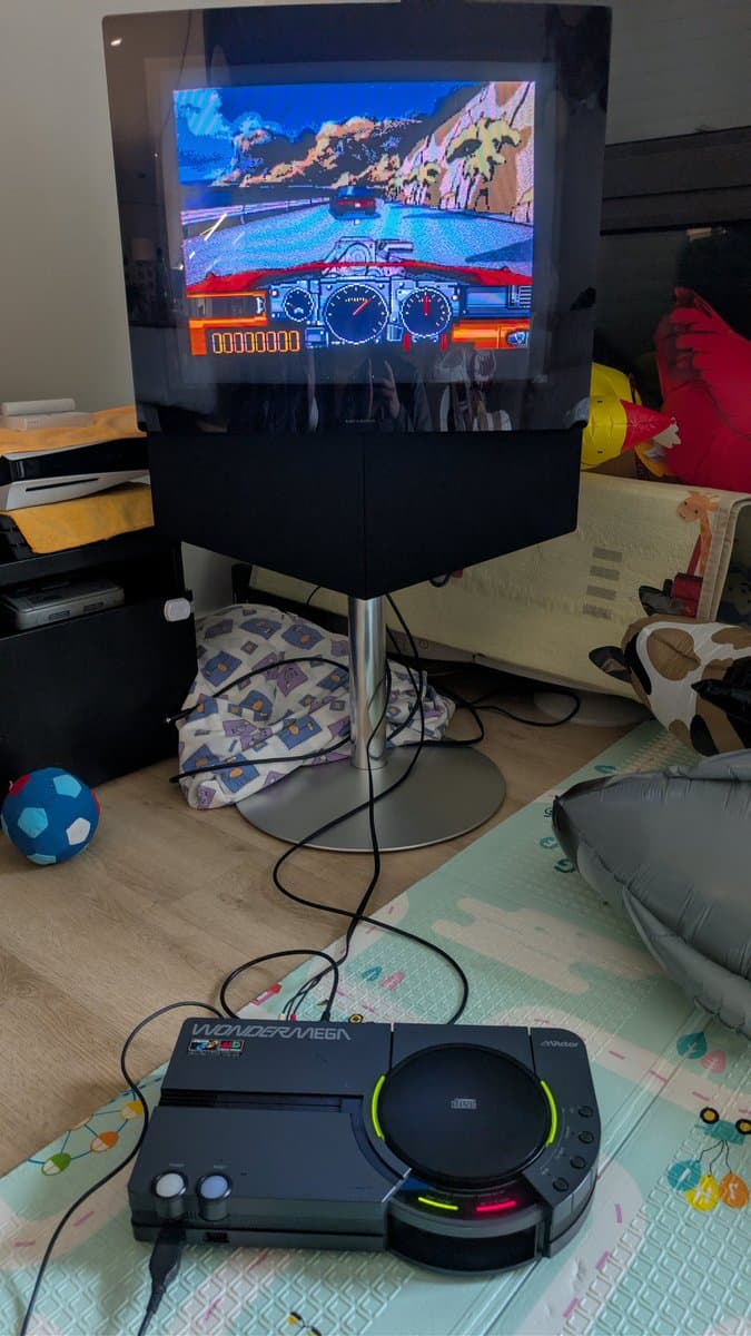 Sega Wondermega displaying Road Avengers on CRT monitor; recapped motherboard with glowing LEDs visible on console below.