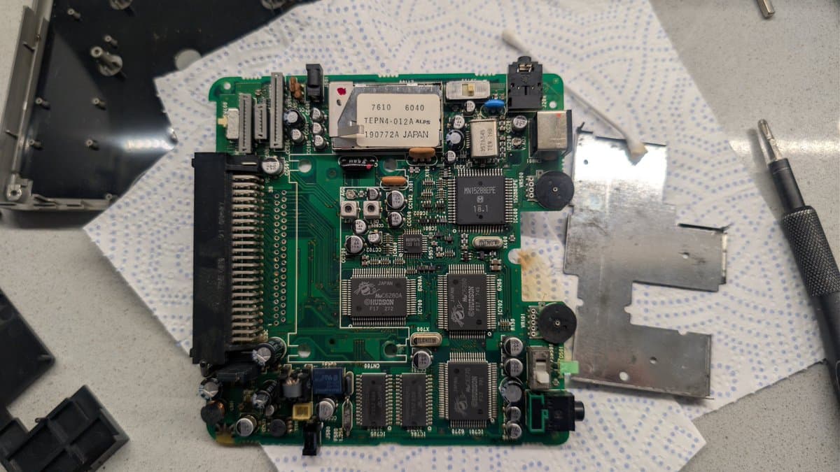 PC Engine LT mainboard with corrosion visible near 6.5V regulator; HuCard slot area cleaned during repair work.