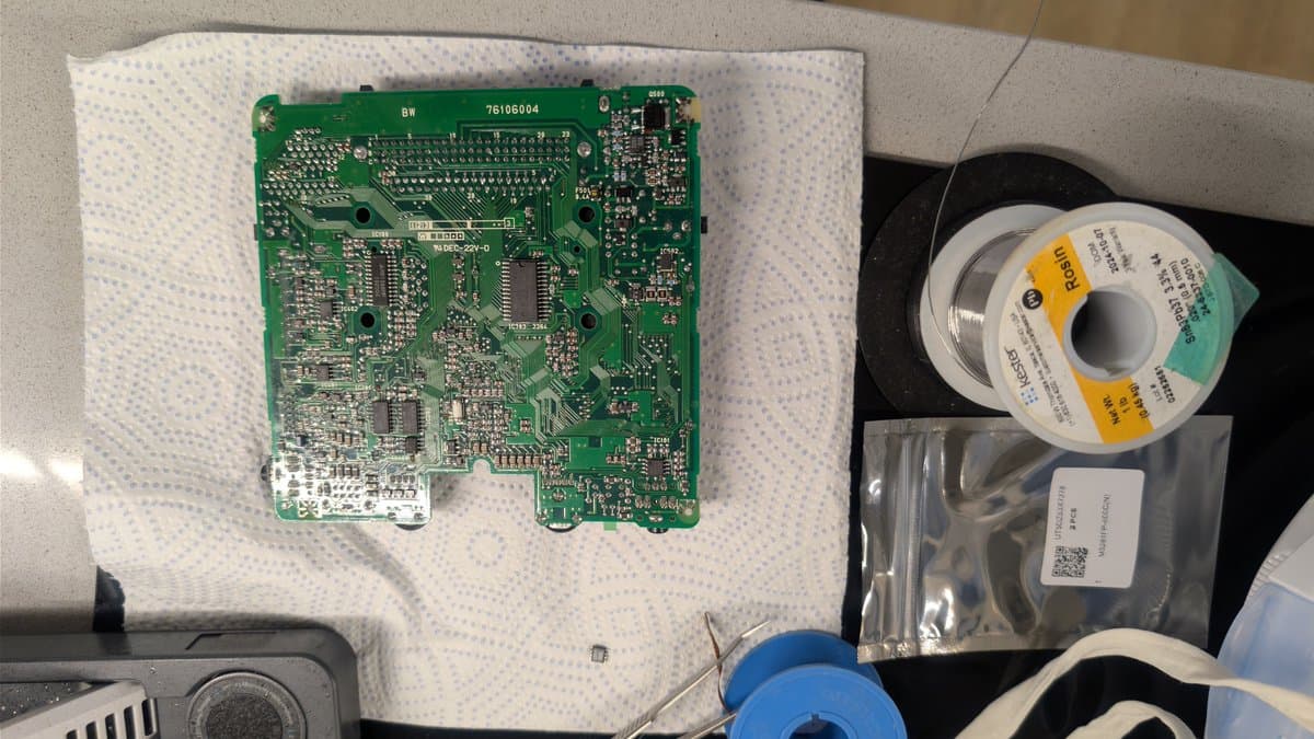 NEC PC Engine LT main board on bubble wrap with removed M5291FP 6.5V regulator IC, solder spool, and replacement components nearby.