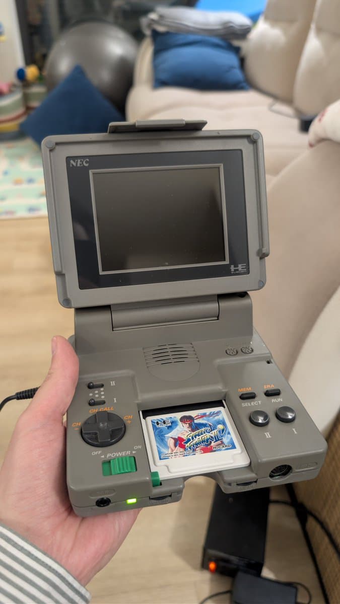 NEC PC Engine LT handheld displaying Strider game cartridge, recapped board visible, troubleshooting in progress.
