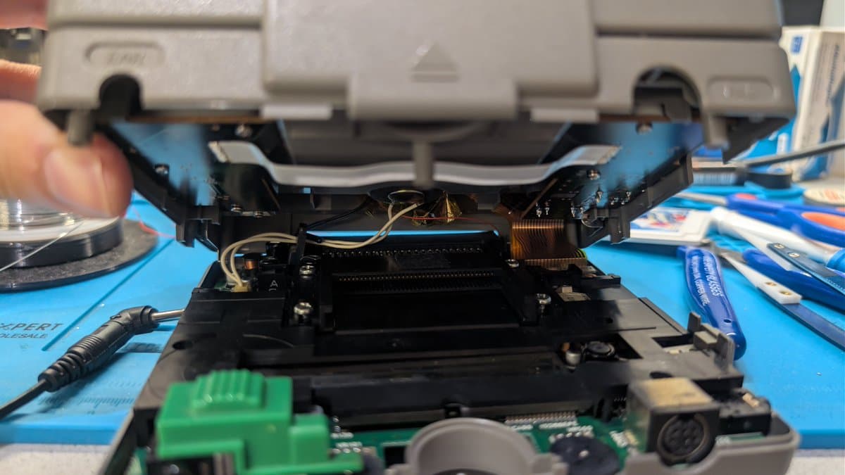 NEC PC Engine LT internal mechanism with replacement component fitted into top shell recess, showing motor assembly and circuit board during repair work.