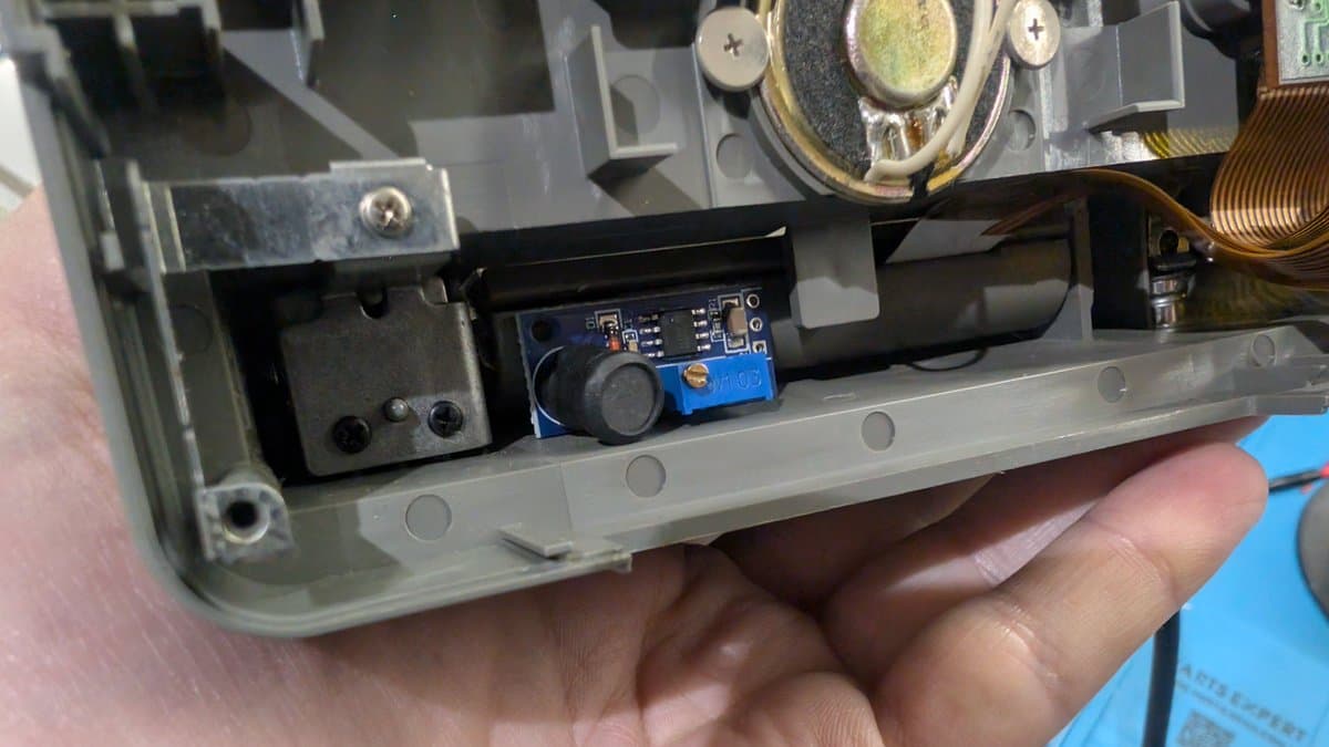 NEC PC Engine LT interior showing blue voltage regulator module fitted into shell recess during repair restoration.