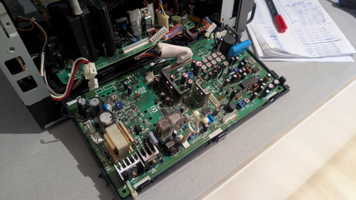 Sony PVM-9041Q deflection board with recapped PSU components visible, marked capacitors, and service documentation on work surface during restoration.