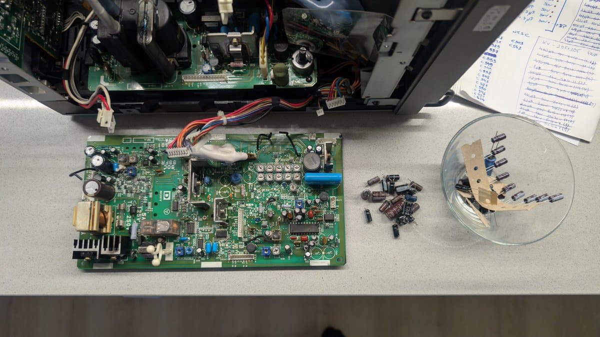 Sony PVM-9041Q PSU board recapped: removed capacitors in clear dish, vinegar-cleaned board showing electrolyte residue areas, schematic notes visible.