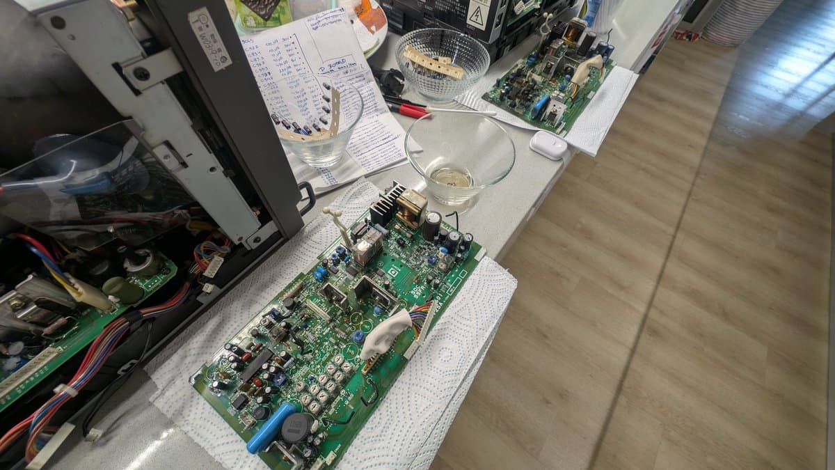Recapped deflection board on white work mat with notes and components; vinegar cleaning stage of Sony PVM-9045QD restoration.