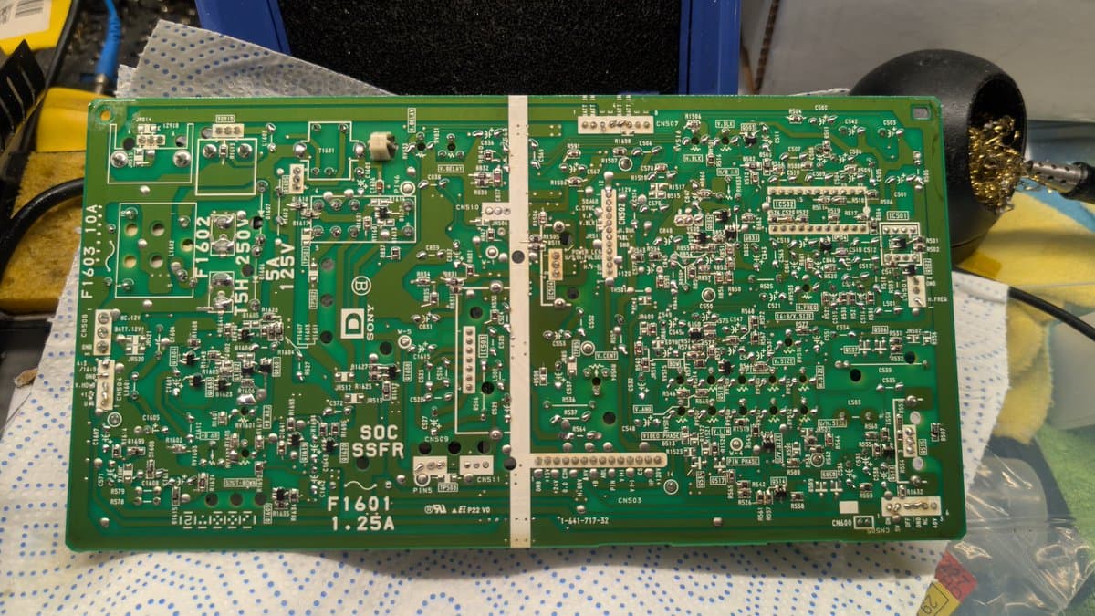 Recapped Sony PVM-9041Q deflection board with fresh solder joints marked with dots; soldering iron visible on right.
