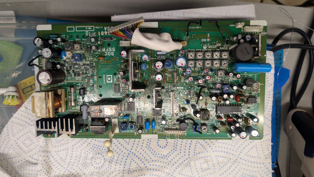 Sony PVM-9045QD PSU board with freshly soldered capacitors marked with dots, shiny solder joints visible on back.