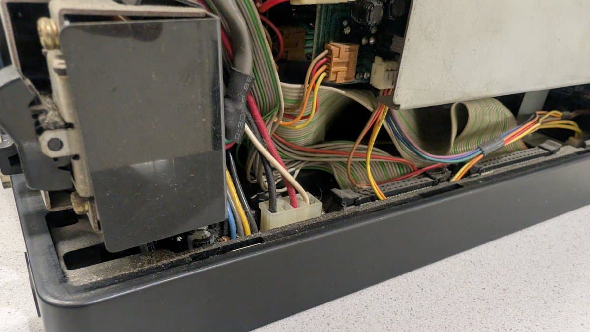 Sharp X68000 interior showing multicolored ribbon cables, circuit boards, and expansion RAM module partially dislodged during shipping.